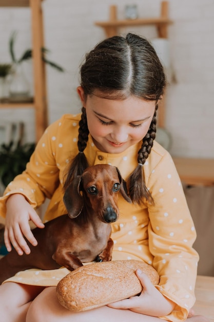 Nettes kleines Mädchen zu Hause in der Küche backt Kekse mit ihrem Hund Dackel