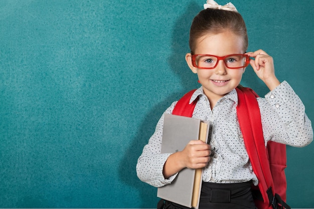 Nettes kleines Schulmädchen in den Gläsern auf Tafelhintergrund