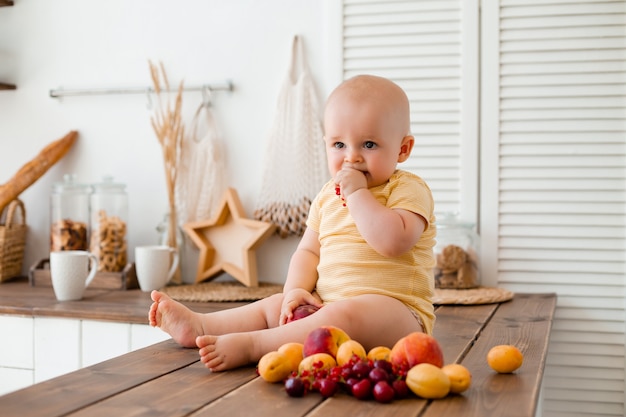 Nettes Kleinkind isst Obst in der Holzküche zu Hause