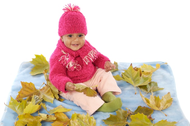 Nettes Kleinkindmädchen, das mit gefallenen Blättern spielt