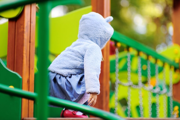 Nettes Kleinkindmädchen, das Spaß auf Freienspielplatz hat