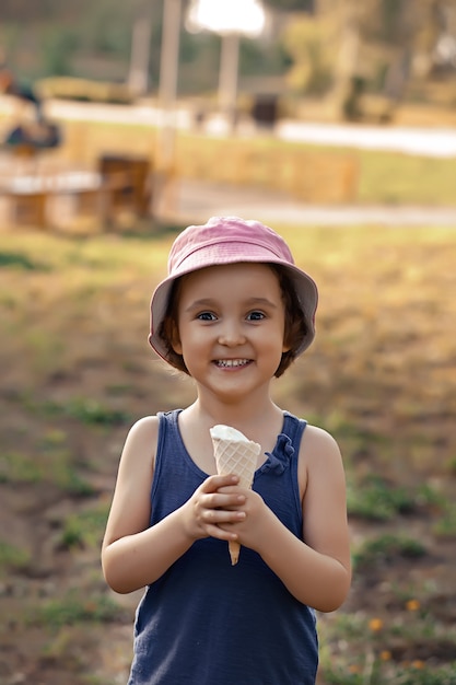 Nettes Kleinkindmädchen in einem Hut, der Eiscreme isst.