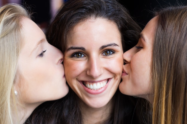 Nettes lächelndes Mädchen küsste von ihren Freunden auf den Wangen.
