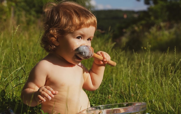 Nettes lustiges Baby mit Löffel im Mund