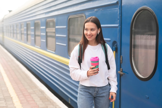 Nettes Mädchen am Bahnhof, der Kaffee hält