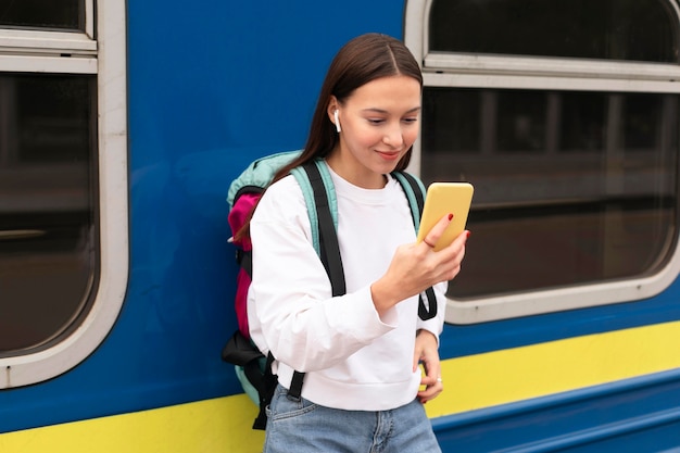 Foto nettes mädchen am bahnhof mit handy