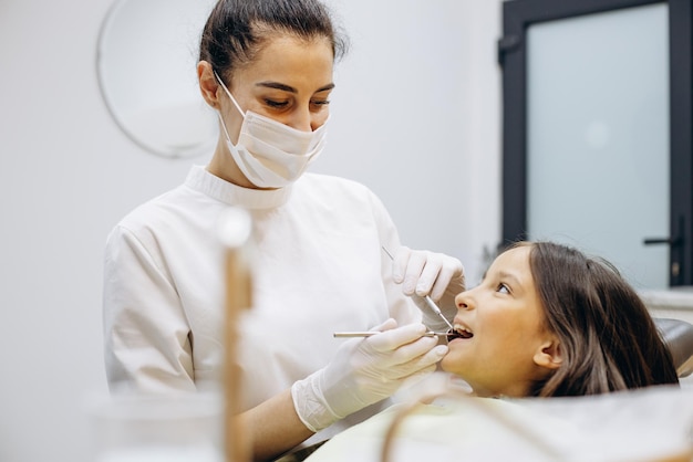 Nettes Mädchen am Zahnarztstuhl, das eine Untersuchung durchführt