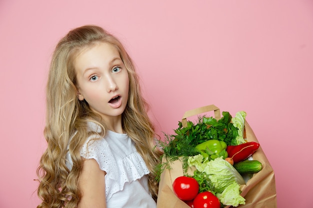 Nettes Mädchen auf einem rosa Hintergrund mit Gemüse
