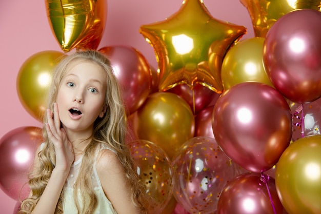 Nettes Mädchen auf einem rosa Hintergrund mit Luftballons