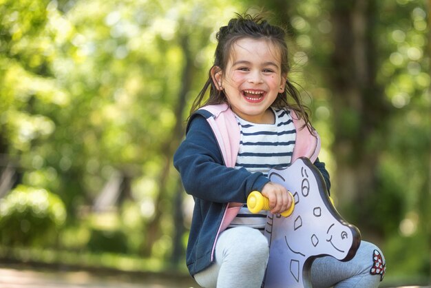 Nettes Mädchen, das auf Spielplatz im Park in der Sommerzeit genießt.