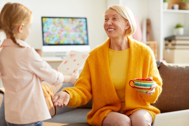 Nettes Mädchen, das der Mutter Karte gibt