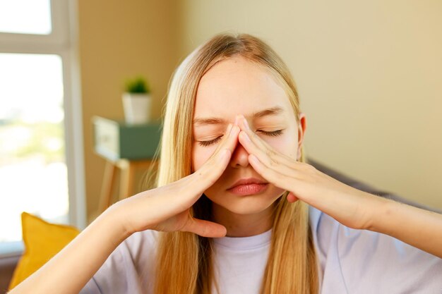 Nettes Mädchen, das Freizeitkleidung mit der Hand auf dem Kopf trägt, wegen Schmerzen im Kopf, weil Stress in der Schule