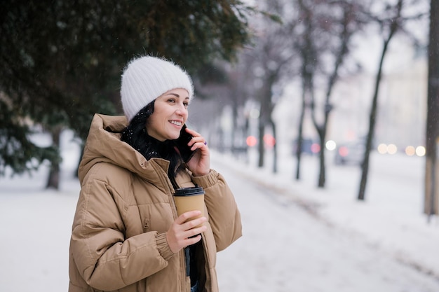 Nettes Mädchen, das im Winter draußen telefoniert und lächelt