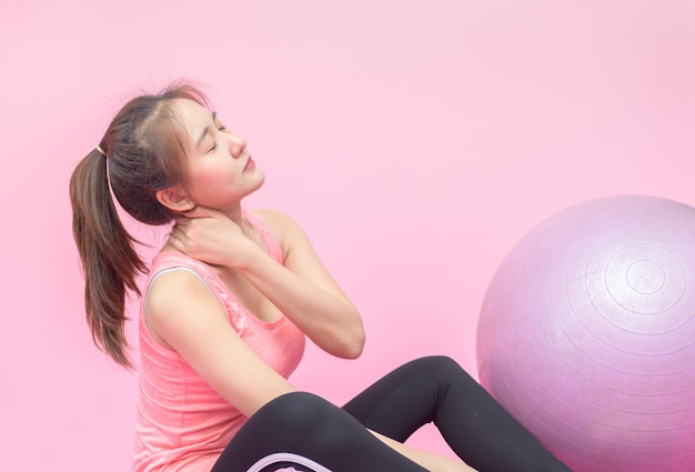 Nettes Mädchen, das Schmerzen in ihrem Nacken während des Trainings im Fitnessstudio hat.