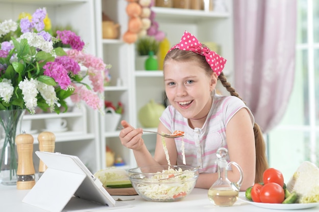 Nettes Mädchen, das zu Hause köstlichen frischen Salat isst