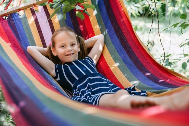 Nettes Mädchen im bunten Hängemattensommerhintergrund, Sommerferien-Outdor-Aktivitäten