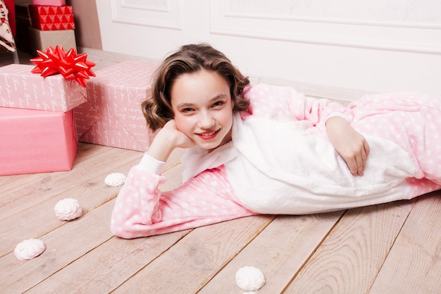 Nettes Mädchen im Pyjama mit Süßigkeiten auf dem Boden