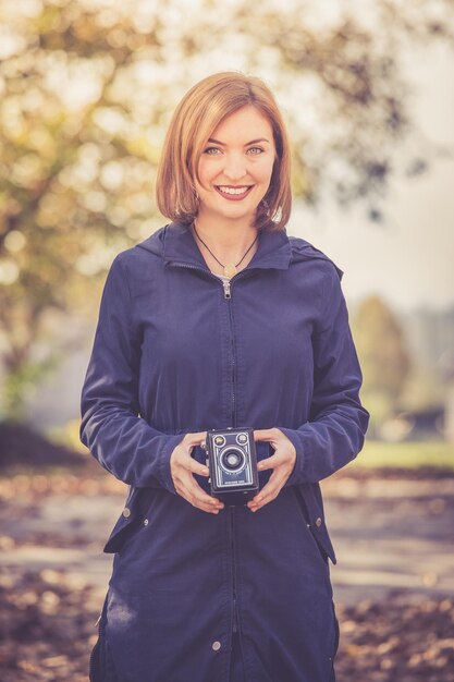 Nettes Mädchen macht draußen Bilder mit einer Vintage-Kamera