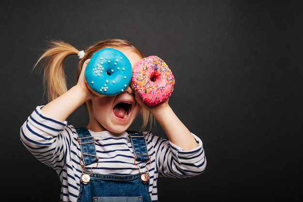 Nettes Mädchen mit Donuts in den Händen