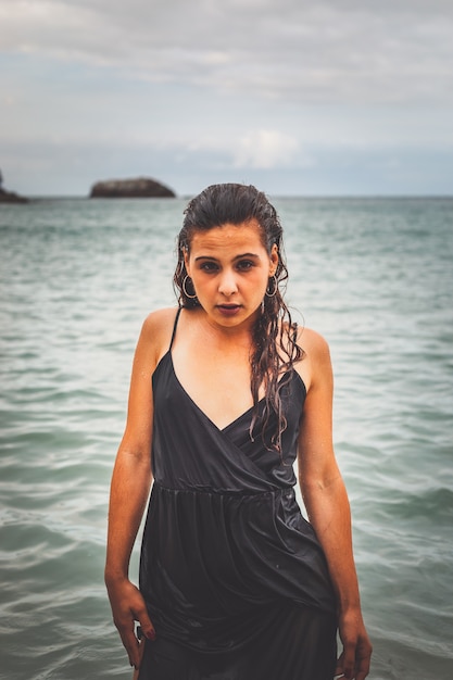 Nettes Mädchen mit einem schwarzen Kleid am Strand