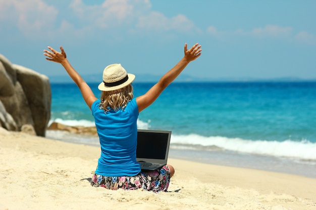 Nettes Mädchen mit Laptop am Meer