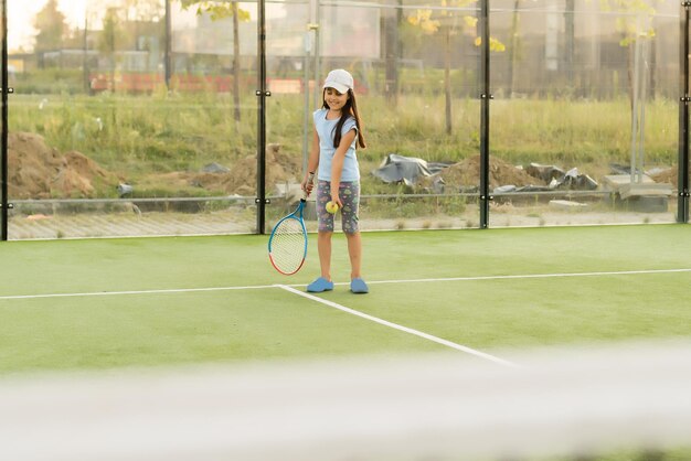 Nettes Mädchen mit Schläger in den Händen, das Tennis spielt