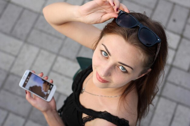 Nettes Mädchen mit Smartphone und Sonnenbrille