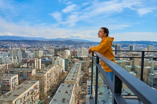 Nettes Mädchen posiert beim Stehen auf dem Balkon des Wolkenkratzers