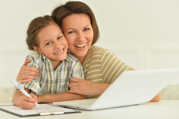 Nettes Mädchen und Mutter mit Laptop zu Hause am Schreibtisch