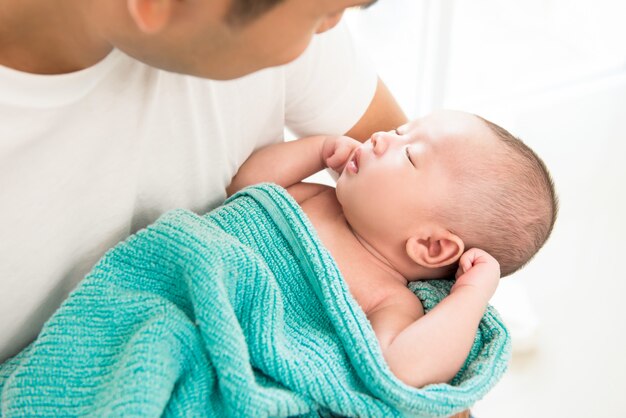 Nettes neugeborenes baby, das in vaterarmen schläft