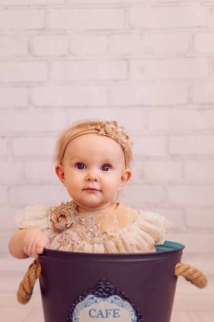 Foto nettes neugeborenes baby in der kreativen dekorationsschaufeltasche. säuglingsmädchen, das innerhalb der schüssel sitzt. pinky farben