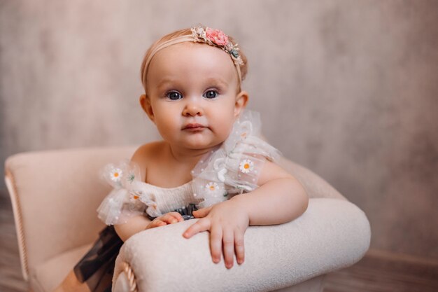 Foto nettes neugeborenes überraschtes baby auf sofa. säuglingsmädchen, das auf speziellen kleinen babymöbeln sitzt