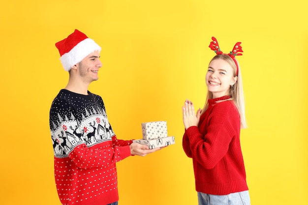 Nettes Paar in Weihnachtskleidung auf gelbem Hintergrund