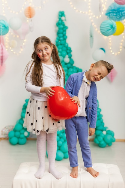 Nettes Paar Kinder mit rotem Herzballon. Valentinstag und Liebeskonzept, Studioaufnahme