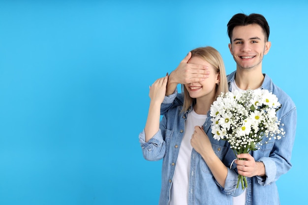 Nettes Paar mit Blumenstrauß auf blauem Hintergrund