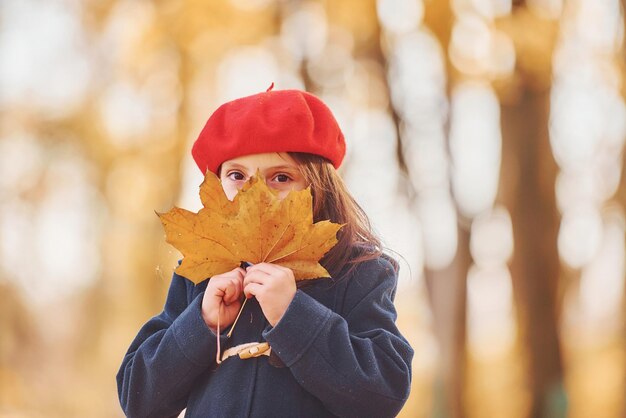 Nettes positives kleines Mädchen hat Spaß im Herbstpark