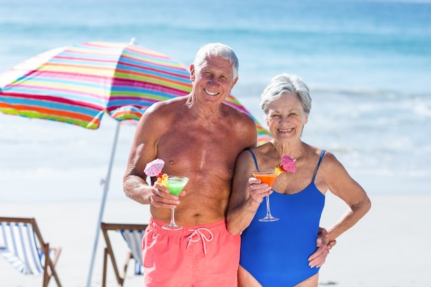 Nettes reifes Paar, das Cocktails am Strand hat