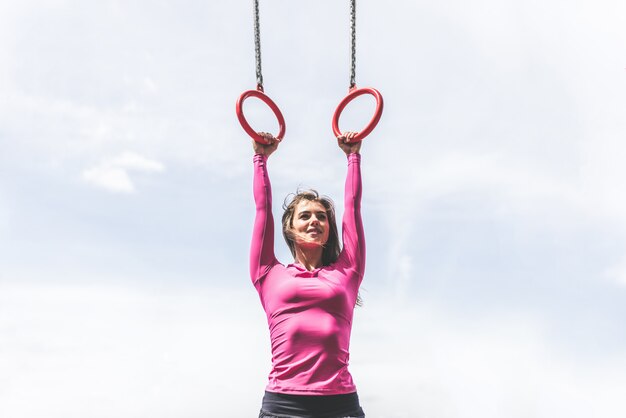 Nettes sportliches Mädchentraining auf den Ringen im Freien