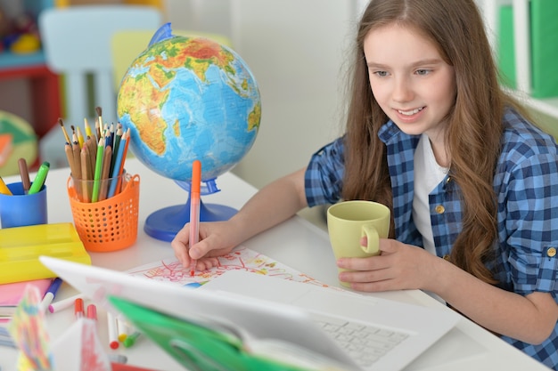 Nettes Studentenmädchen im Unterricht mit Laptop und Tee