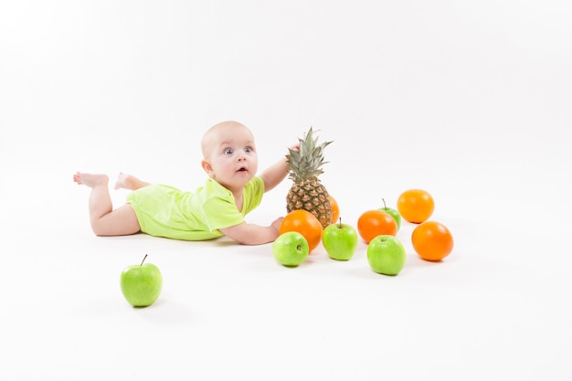 Nettes überraschtes Baby, das Frucht auf weißem Hintergrund einschließlich schaut