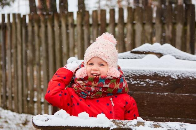 Nettes verspieltes Mädchen im Freien, das den ersten Schnee genießt.