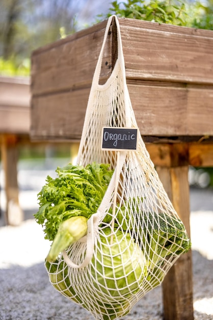 Netzbeutel voller frisches Gemüse, das im heimischen Garten hängt