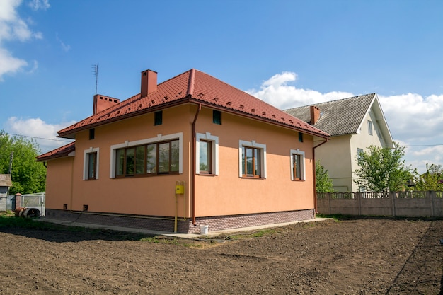 Neubau eines einstöckigen Ferienhauses mit rotem Ziegeldach, Kunststofffenstern, verputzten Wänden und hohen Kaminen