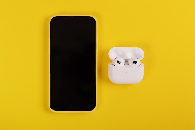 Neue AirPods 3 und iPhone auf gelbem Hintergrund