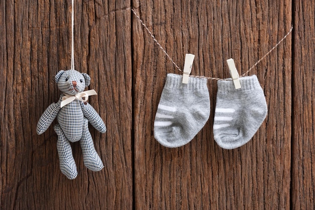 Neue Babysocken, die an der Wäscheleine über Holzhintergrund hängen Neugeborenes und Babykonzept