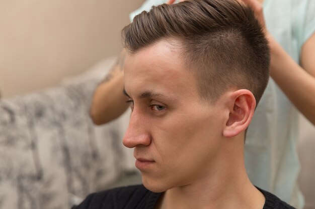 Neue Frisur am Ende Seitenansicht des jungen Mannes, der beim Friseur gepflegt wird