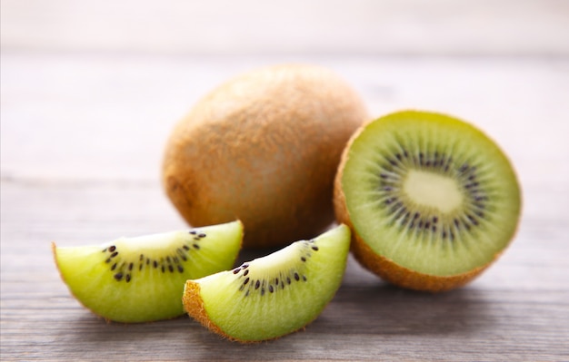 Neue Kiwi und Scheiben der Kiwi auf grauem hölzernem Hintergrund