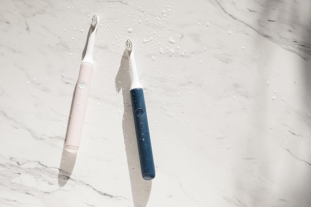 Neue moderne Ultraschallzahnbürste mit Spritzern und Wassertropfen auf Marmorhintergrund. Mundhygiene, Zahn- und Zahnfleischgesundheit, gesunde Zähne. Dentalprodukte Ultraschall-Vibrationszahnbürste.