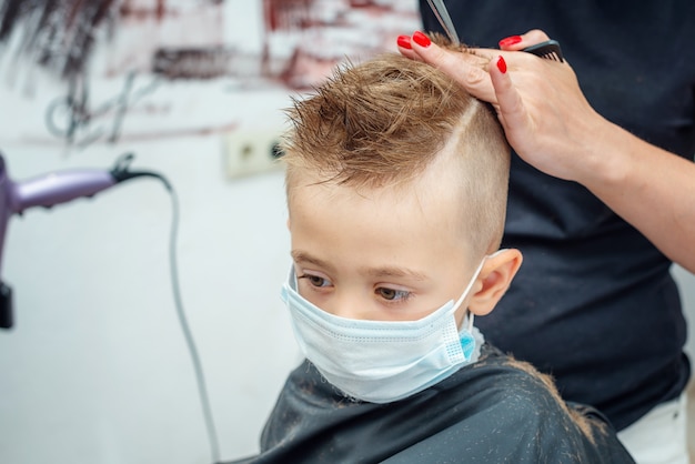 Neue normale anpassung an das normale leben nach einer pandemiesperre. junge bekommt haarschnitt tragen maske.