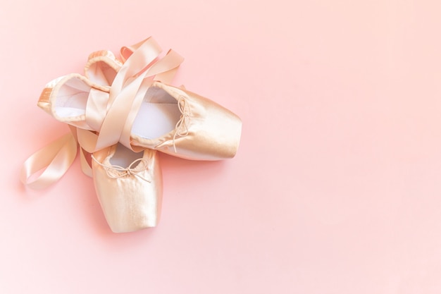 Neue pastellbeige ballettschuhe mit satinband lokalisiert auf rosa hintergrund